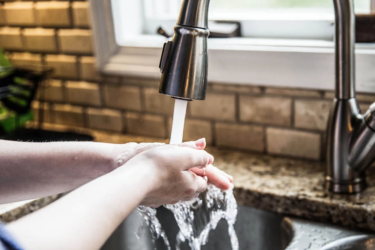 teenage girl washing hands in kitchen