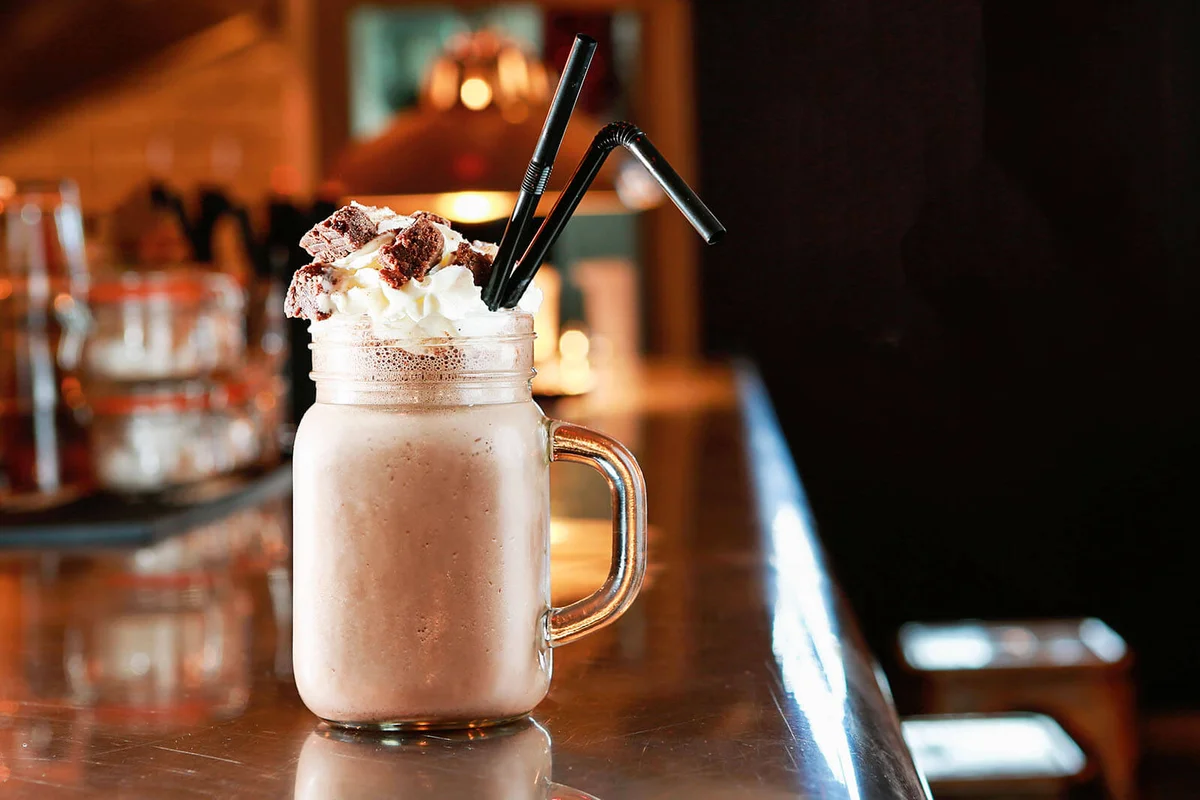 chocolate milkshake topped with cream and milk chocolate flake pieces