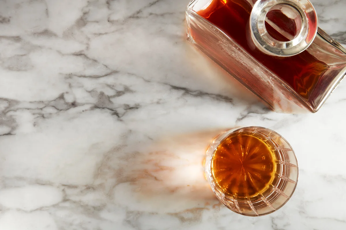whiskey bottle and crystal rock glass on marble