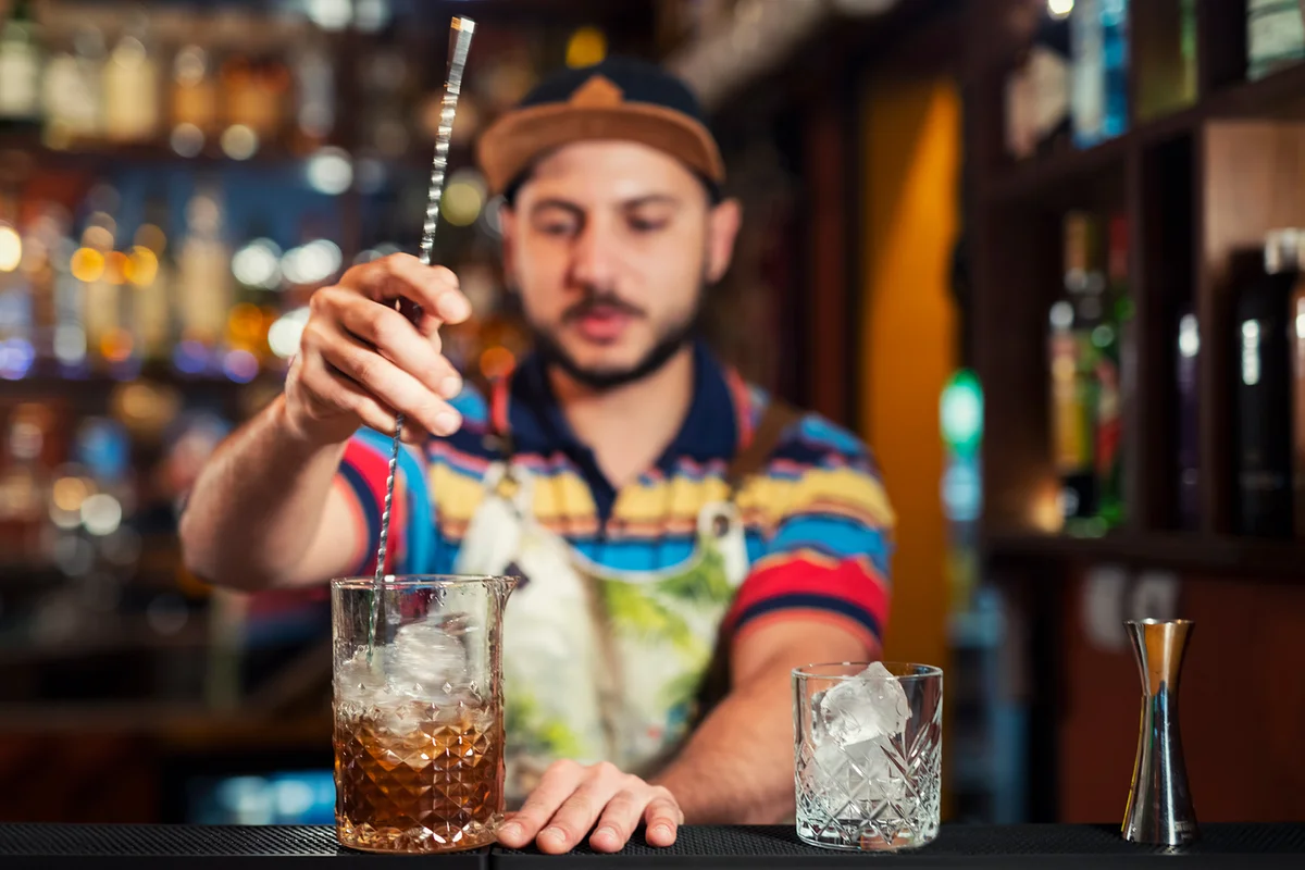 bartender stirring cocktail in glass
