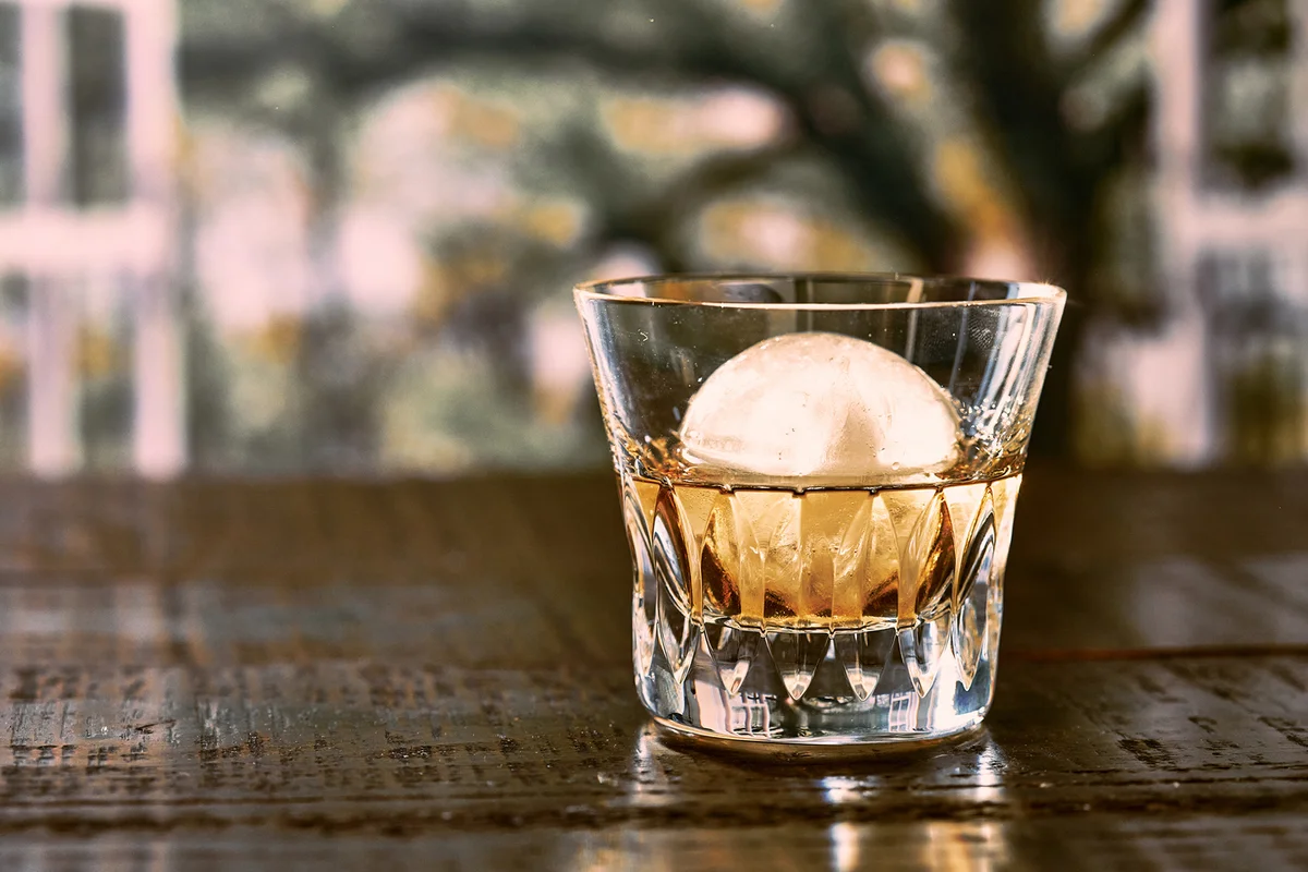 The cut glass contains whiskey and round ice