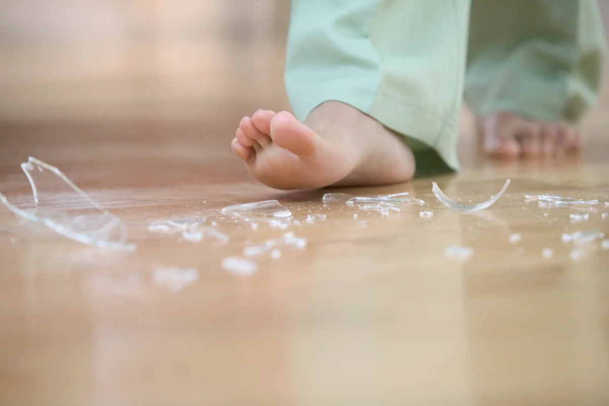 Person walking bare feet with broken glass on the floor