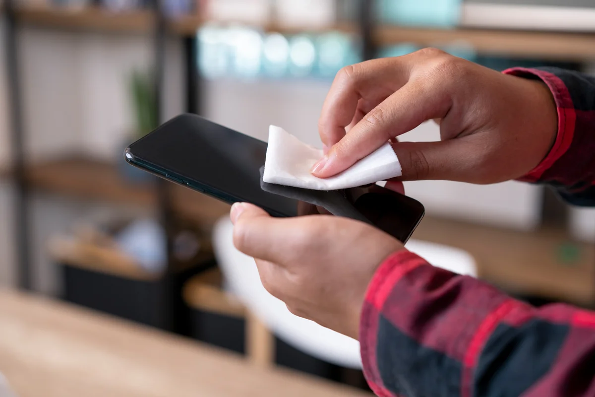 Man cleans his smart phone in the office