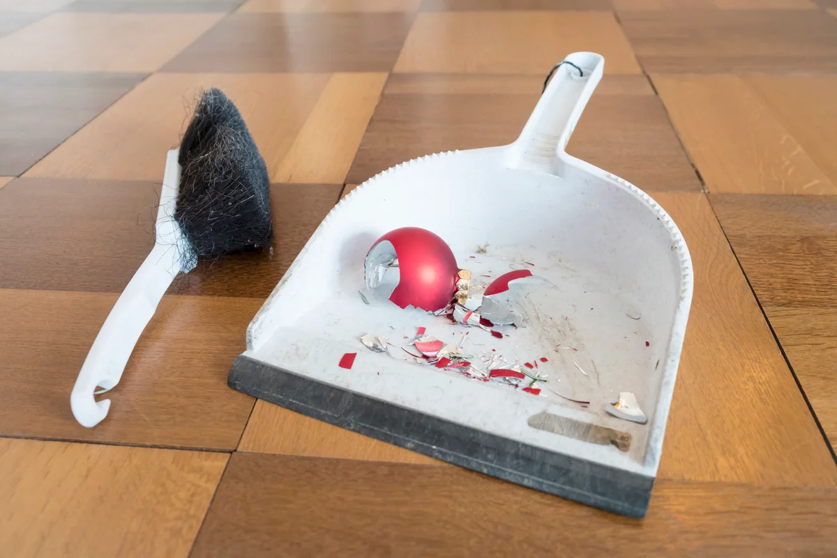 Sweeping up shards of a shattered Christmas bauble on the floor