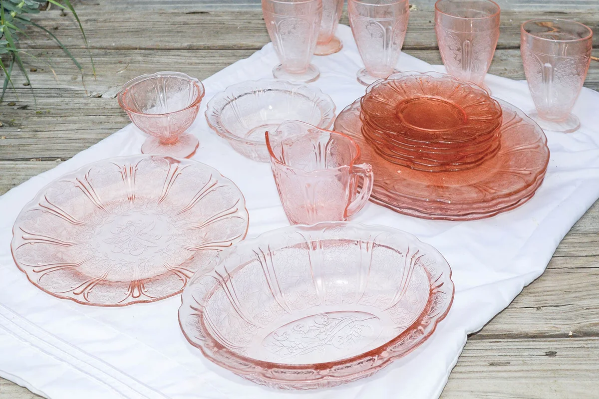 Select pieces of vintage Cherry Blossom Depression Glass on a white cloth