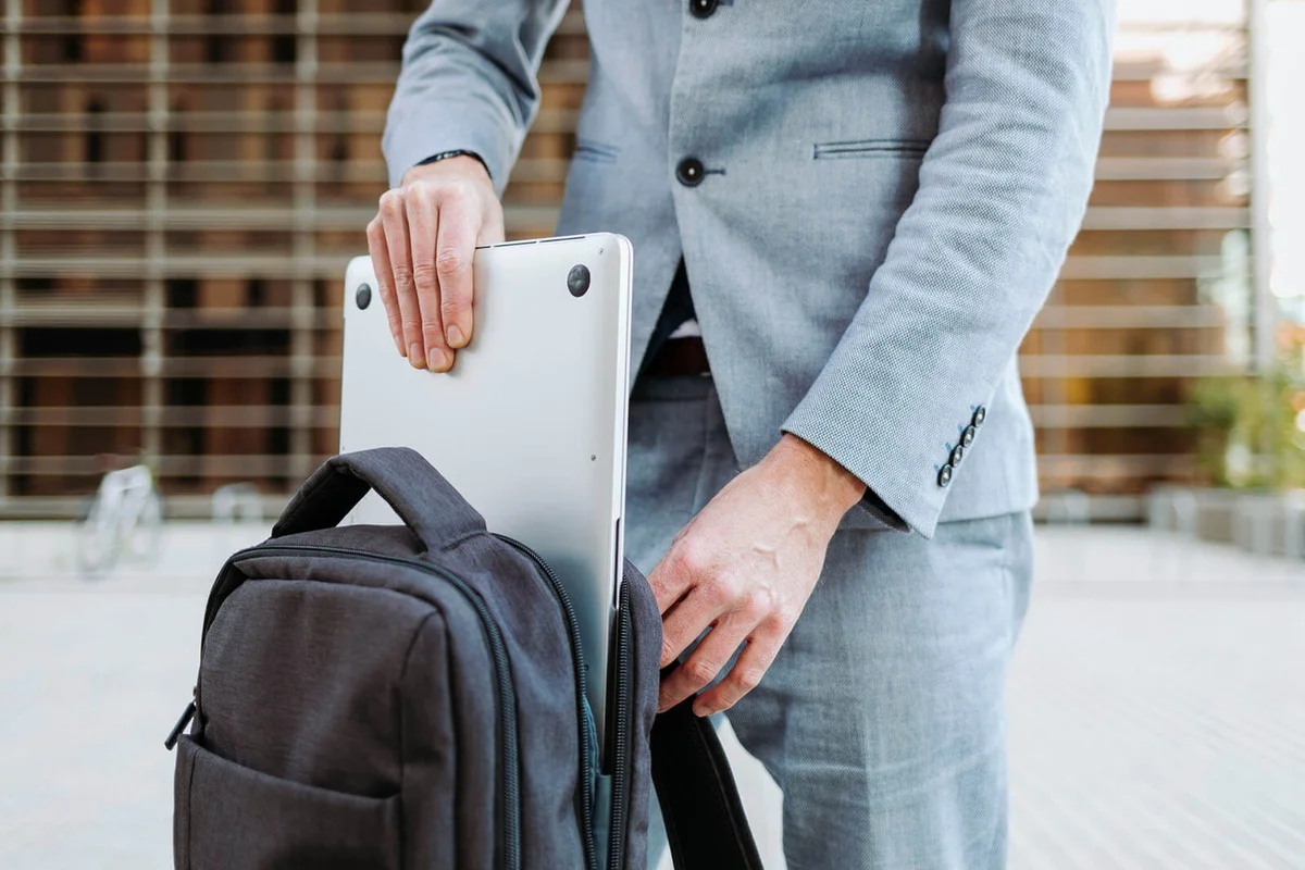 Businessman taking out laptop from back pack