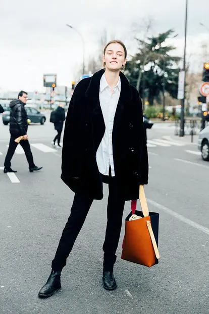 Laura Kampman wears an all black outfit with a white shirt and carries a Celine twisted cabas bag