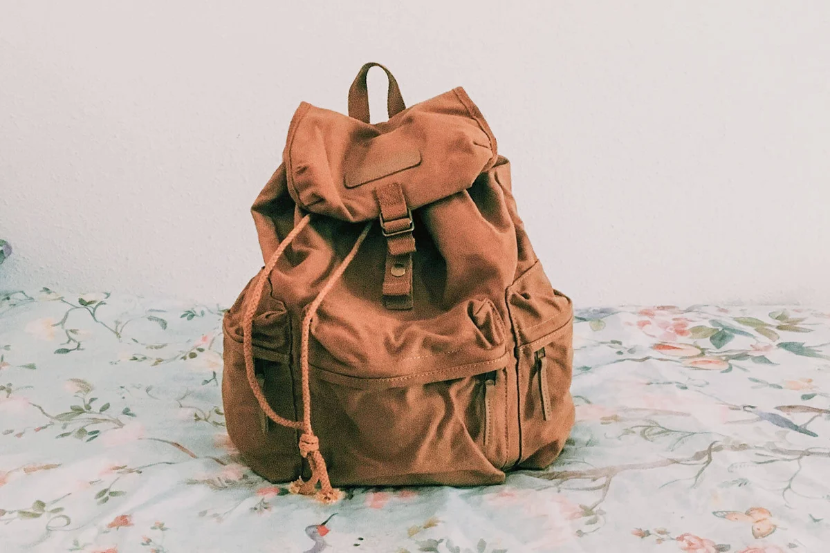 Brown Backpack On Bed By Wall In Room