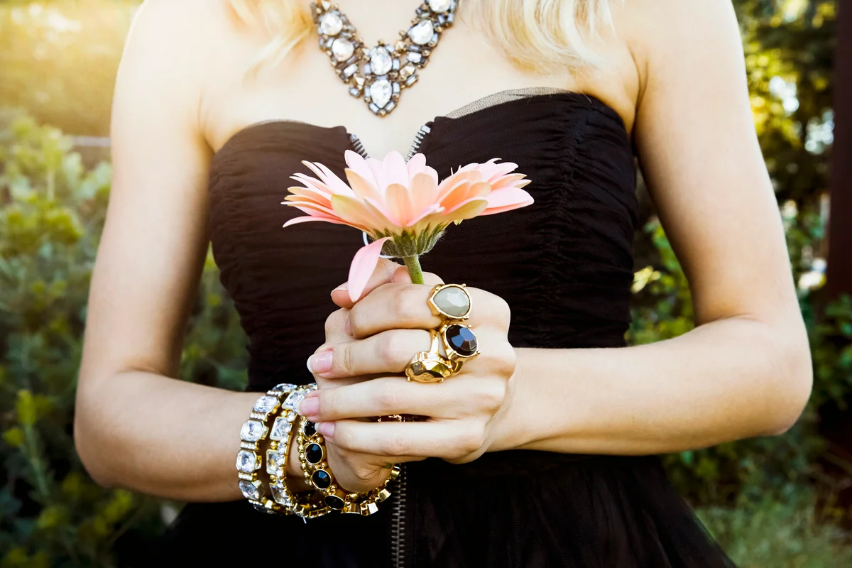 Woman with a lot of jewellery holding a fresh flower