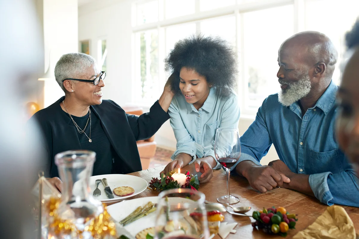 Teenage girl talking with family at dining table