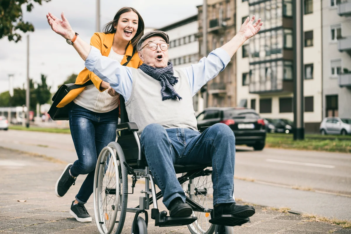 Young woman pushing senior man in wheelchair