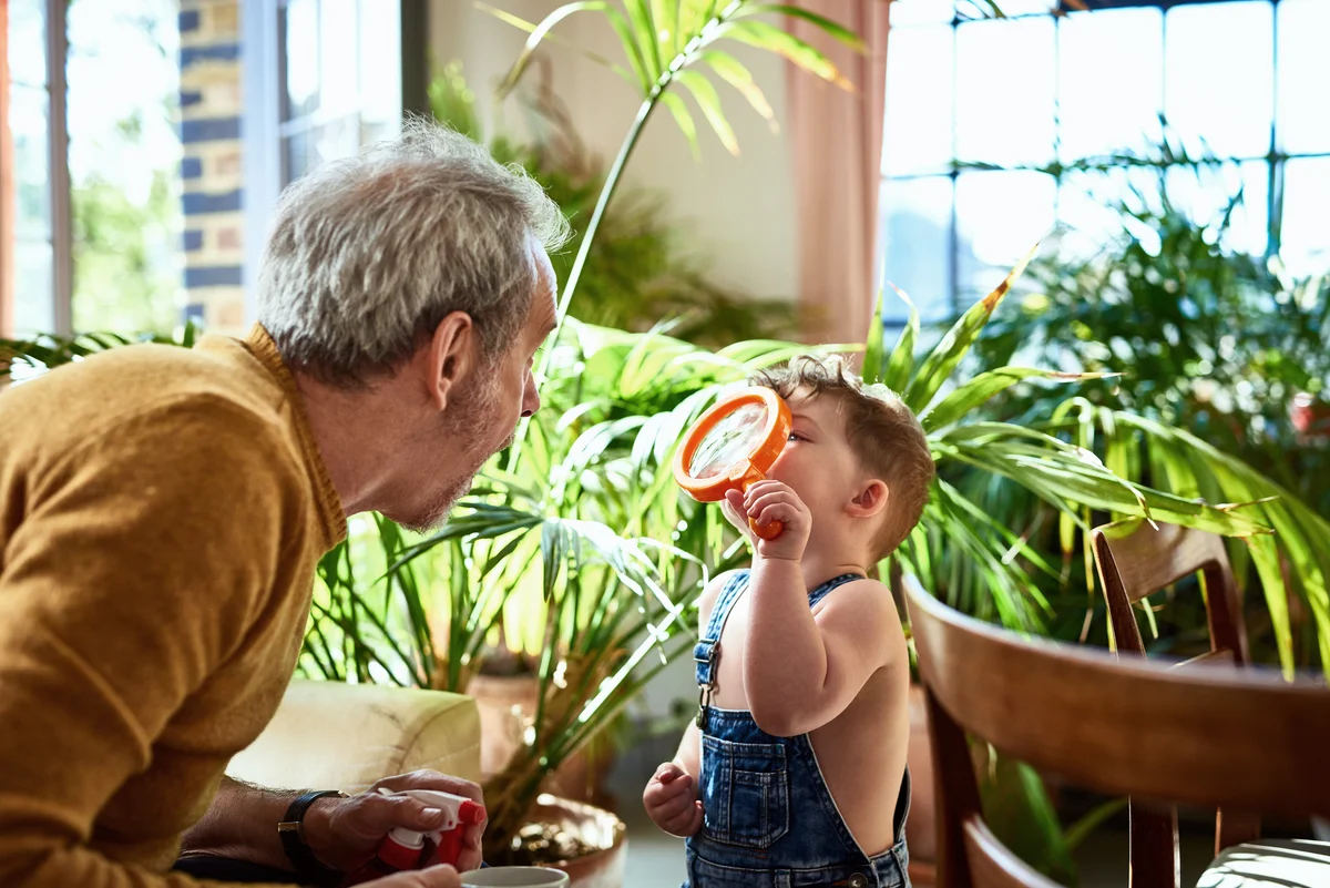 Grandson studying grandfather's face through magnifying glass