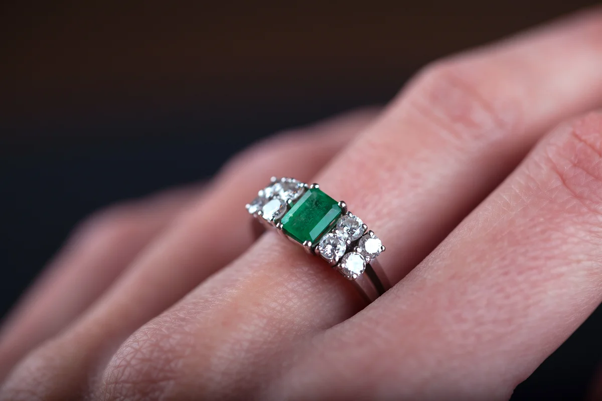 emerald ring in woman finger, with diamonds and platinum