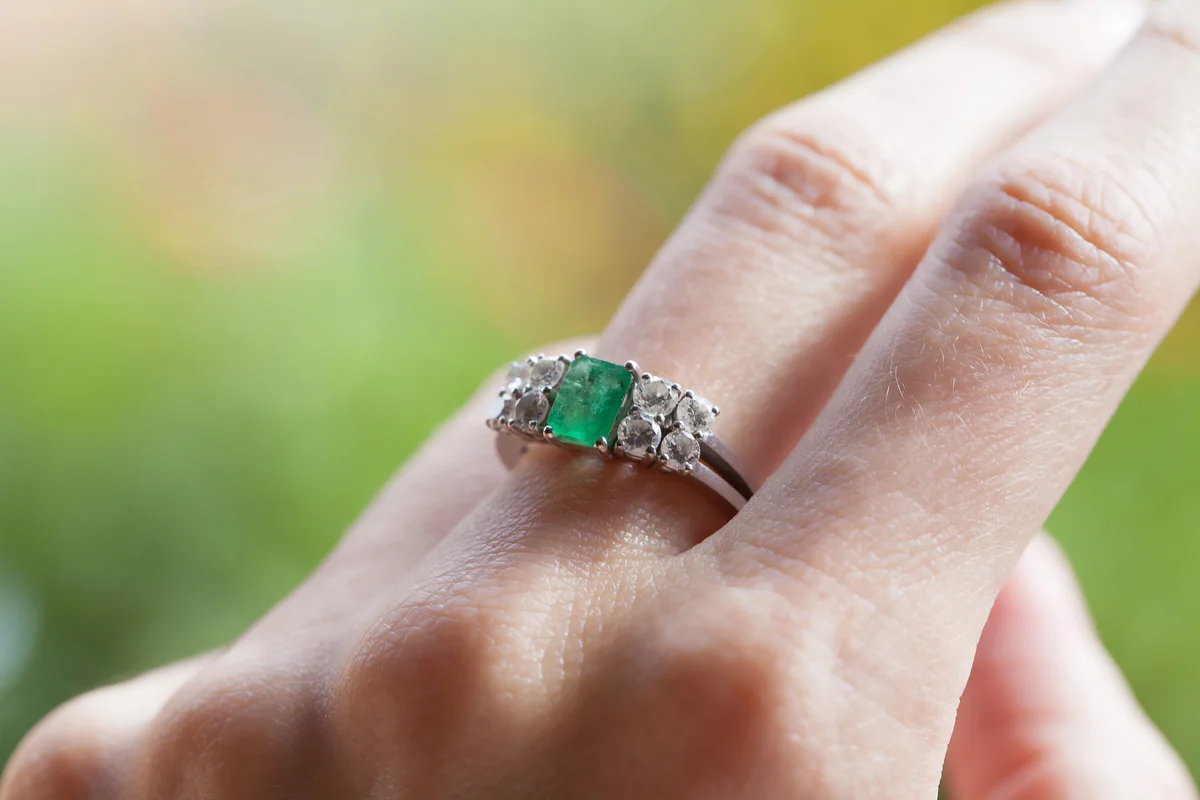Emerald and diamond ring in finger