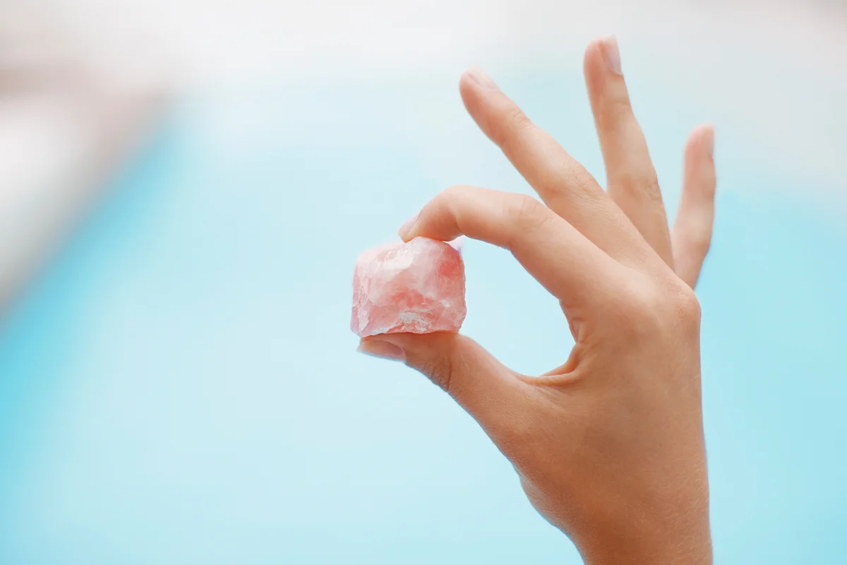 Hand holding rose quartz at poolside