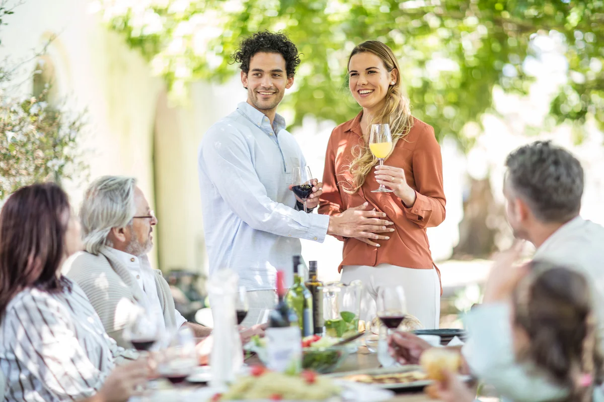 Young couple raising a toast with announcement of pregnancy to family during event