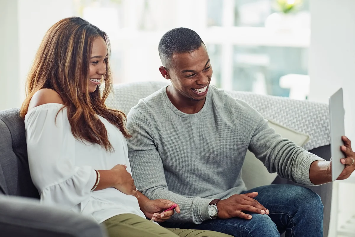 couple video calling using a tablet to share the news that they expecting a baby at home