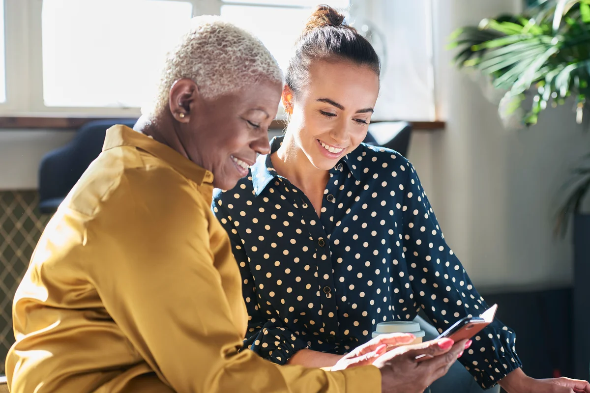 Senior woman and young woman looking at mobile phone