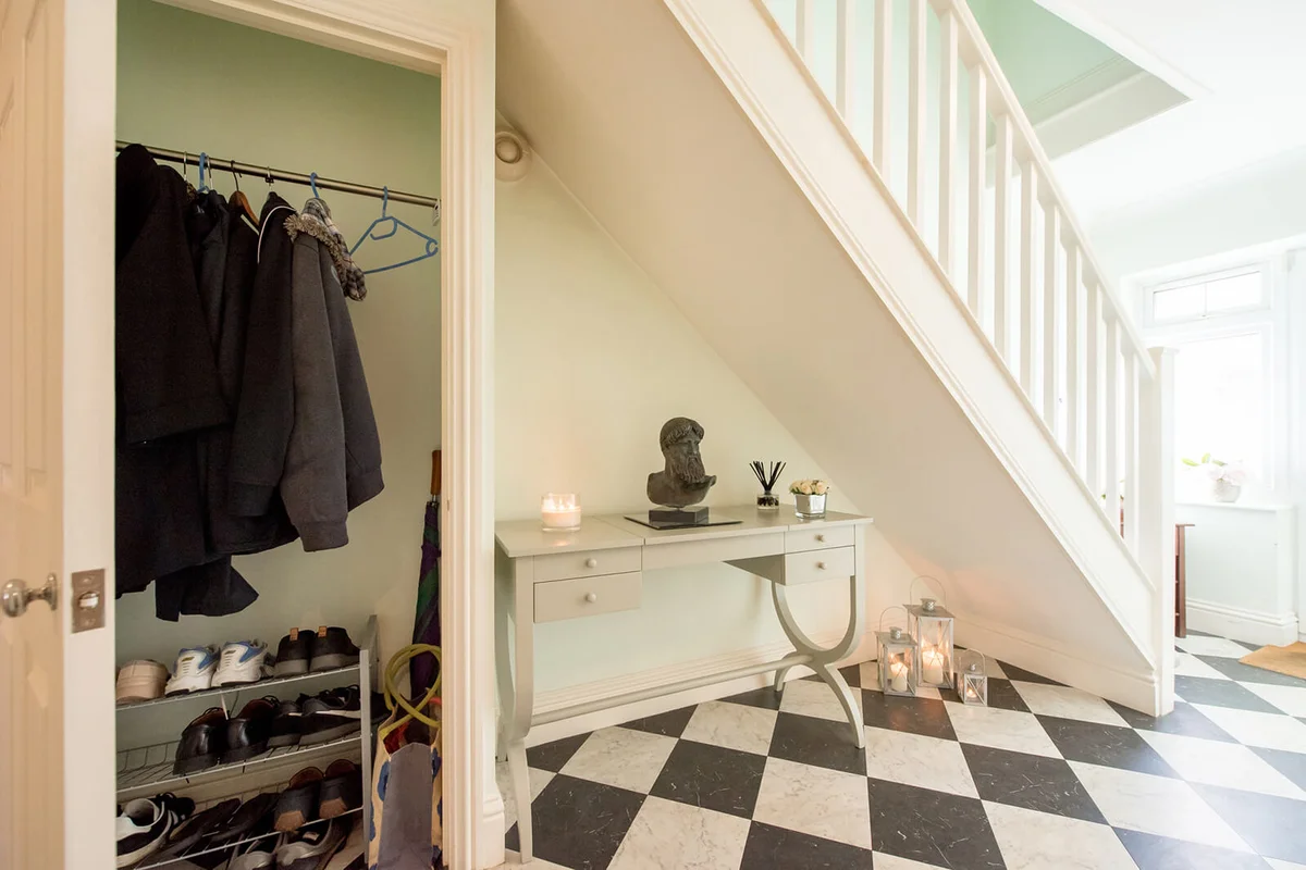 bright hallway showing under stairs cupboard storing coats and shoes within a home