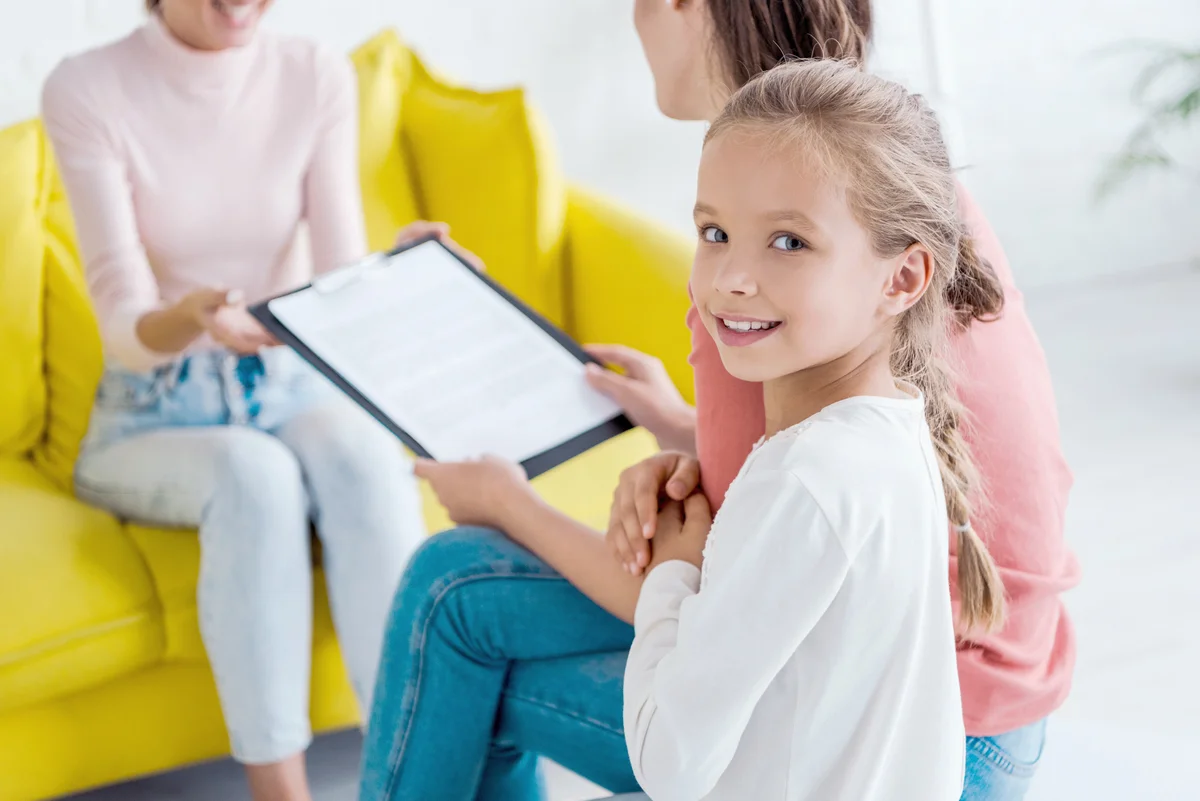 Child smiling near mother and babysitter at home