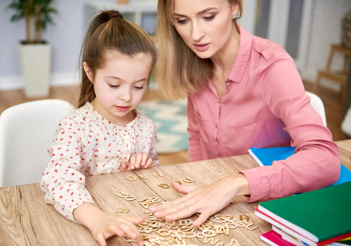 Focused child learning the alphabet with her nanny