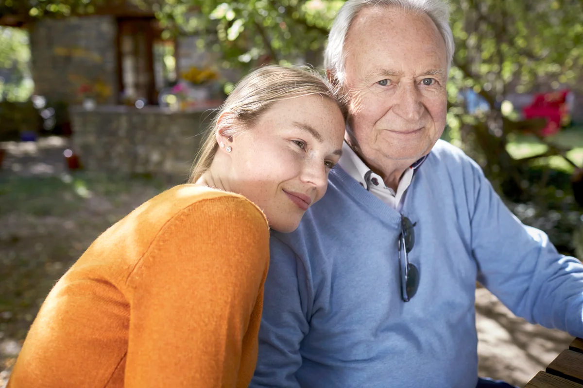 Smiling senior man and young woman in garden