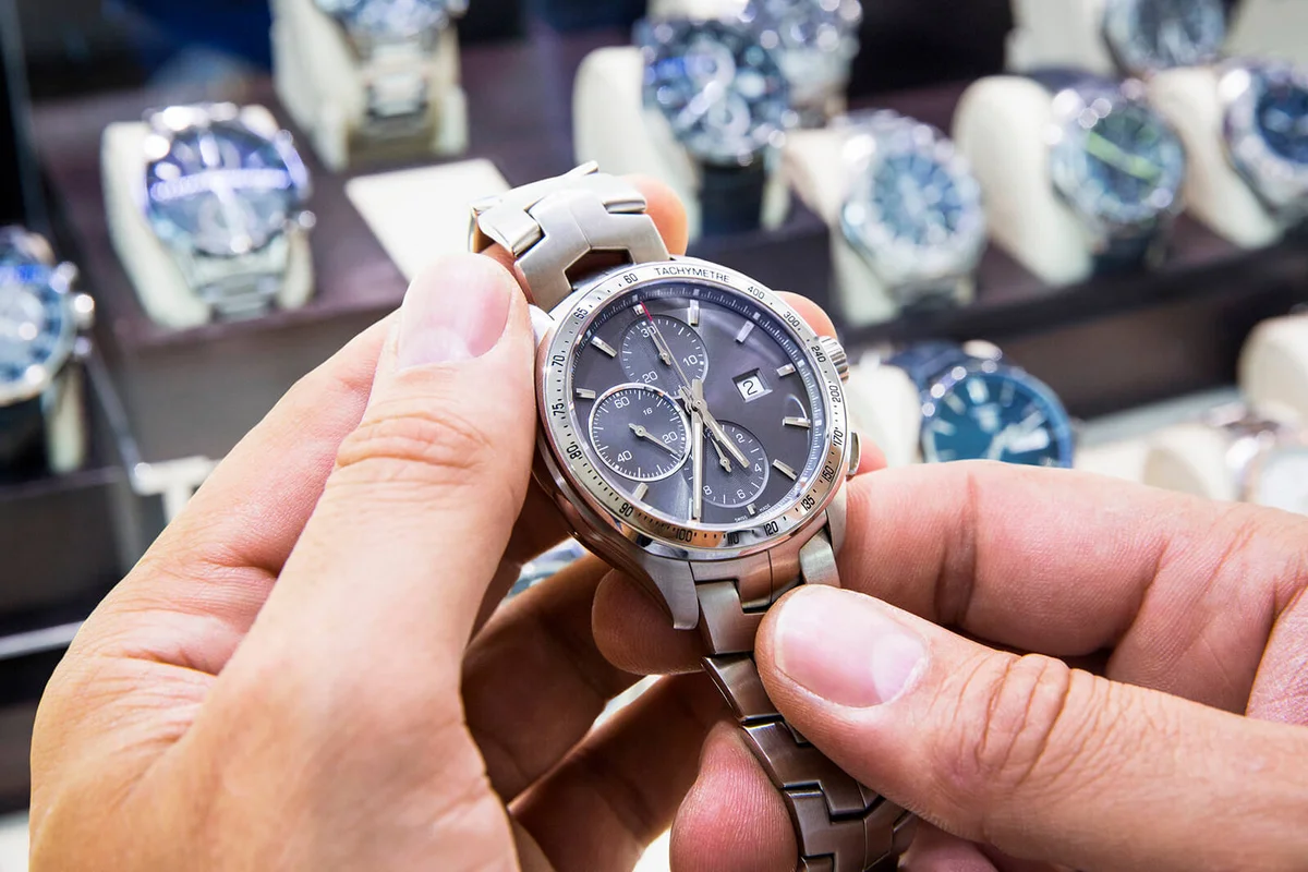 Mens wristwatch being held in a watch shop