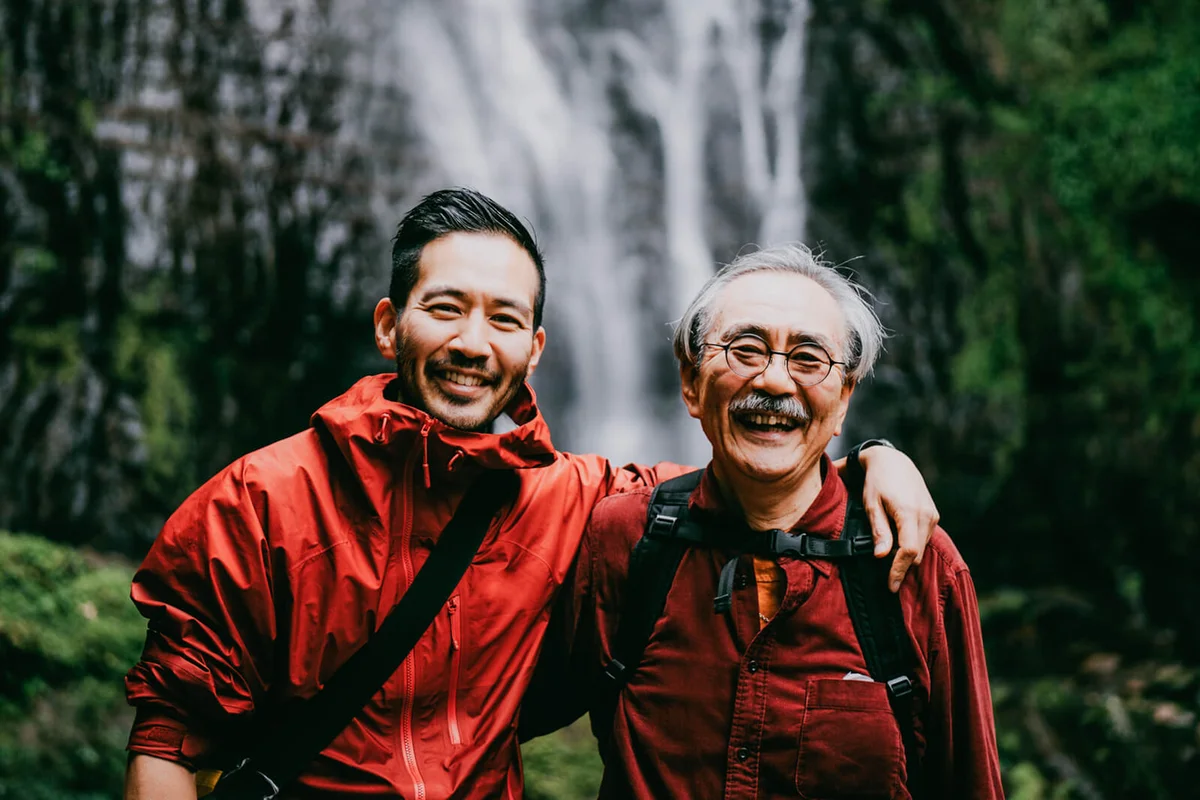Father and son smiling at camera in nature
