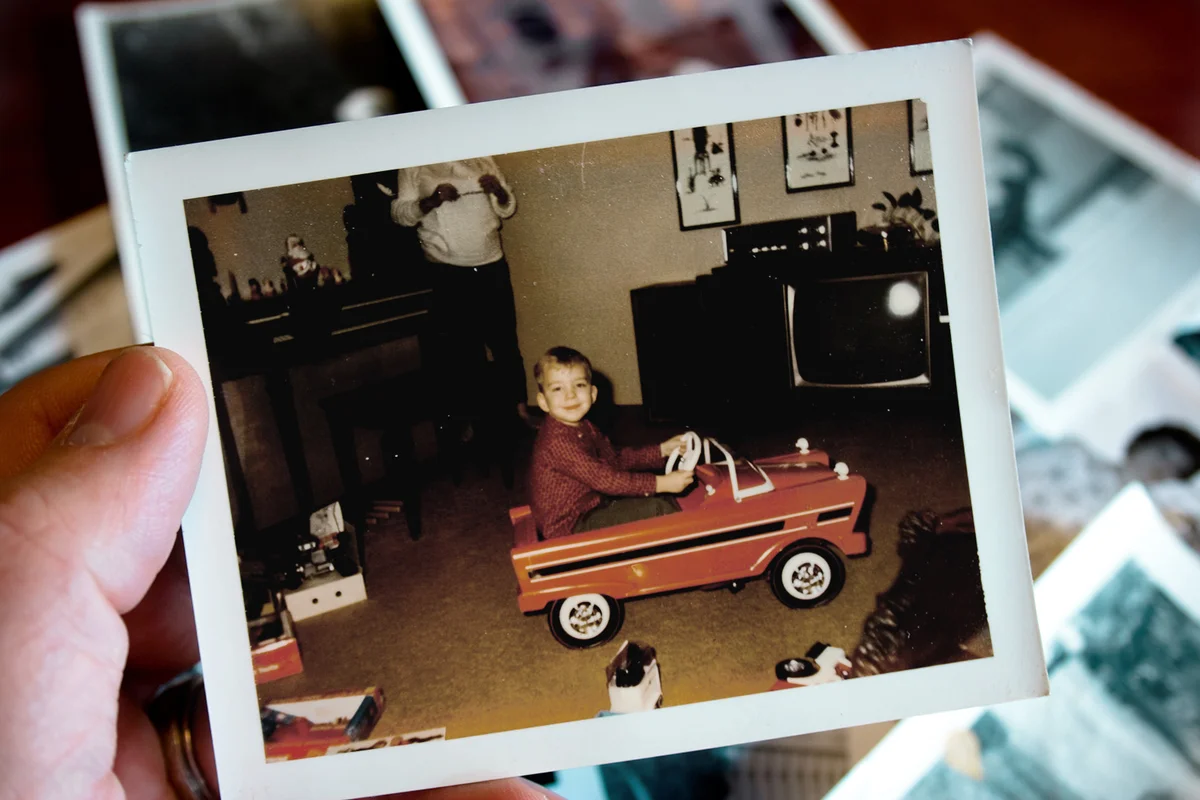 Hand holds Vintage photograph of boy in pedal car