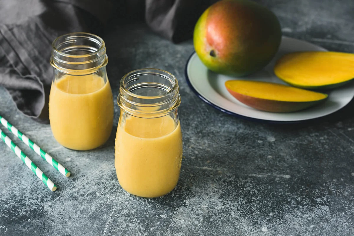 Mango smoothie in bottle on concrete background