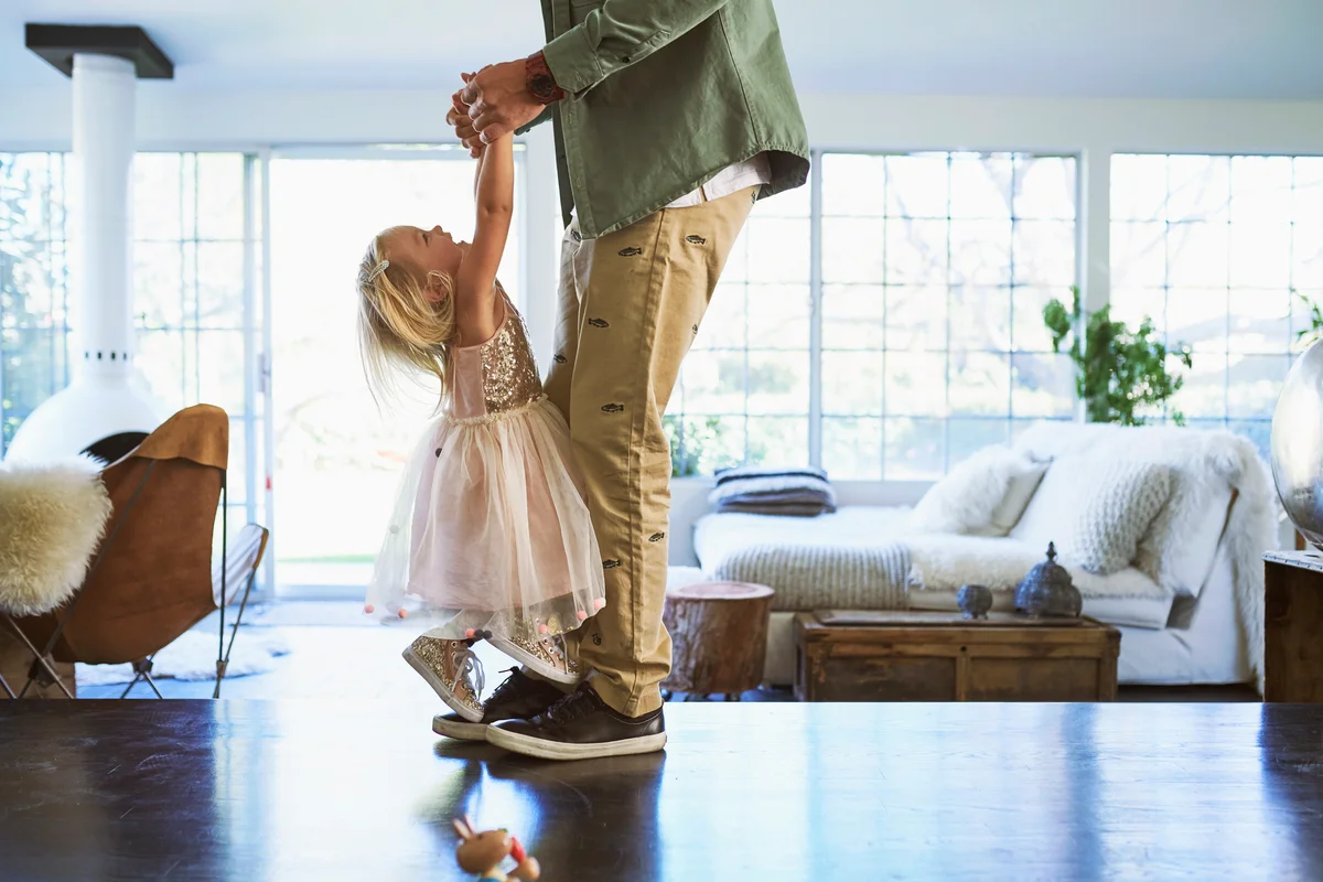 Daughter standing on feet of father dancing