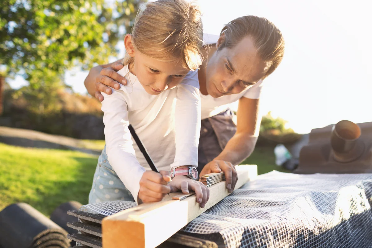 Father assisting daughter in measuring plank