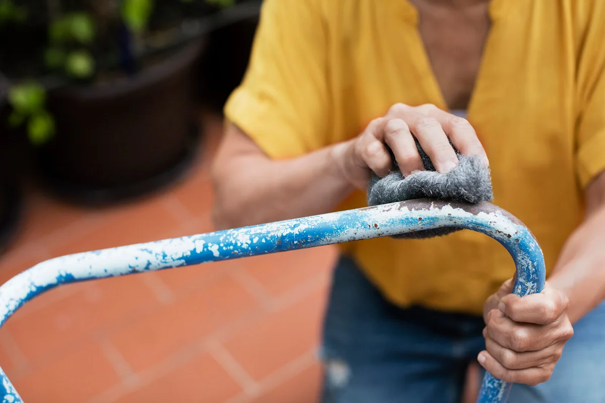 Midsection of woman scrubbing chair with steel wool at yard