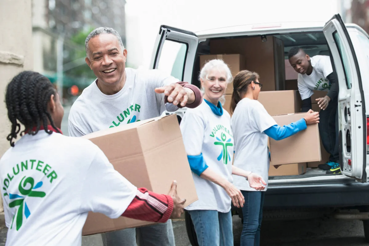 Volunteers passing cardboard boxes from delivery van