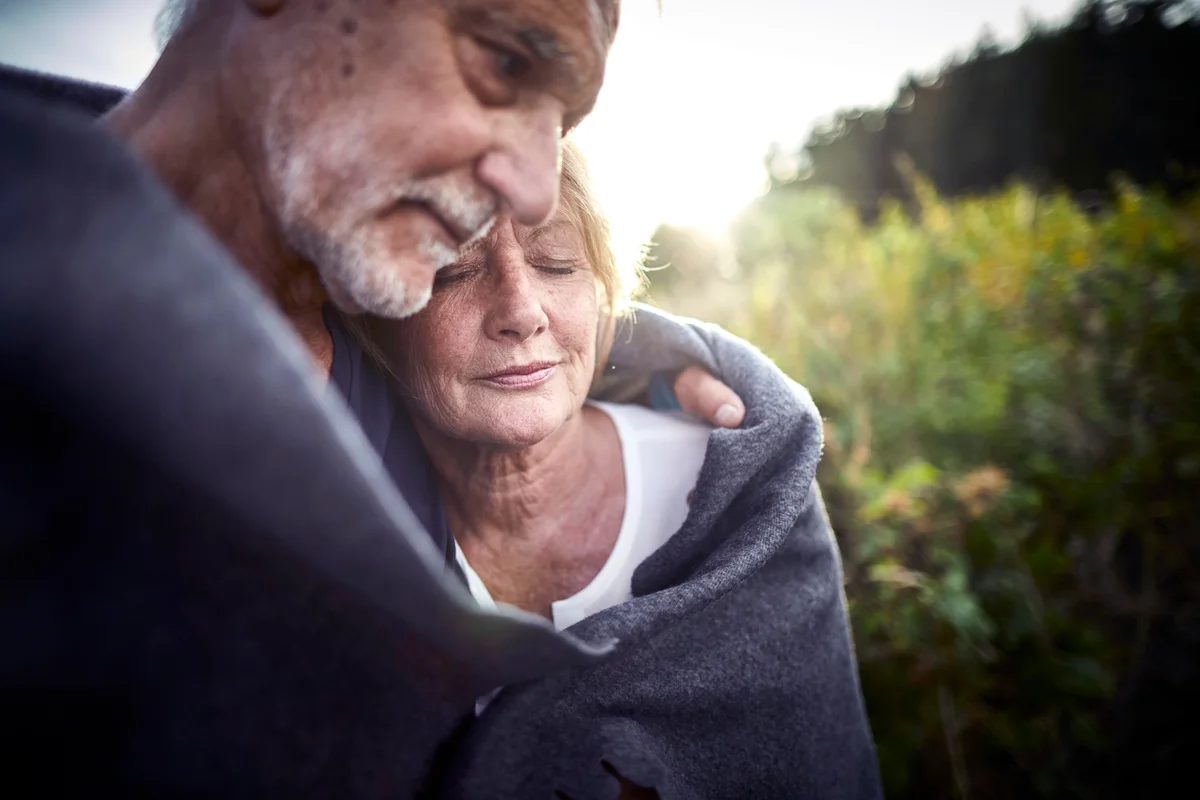 Mature couple wrapped in a blanket cuddling in silence