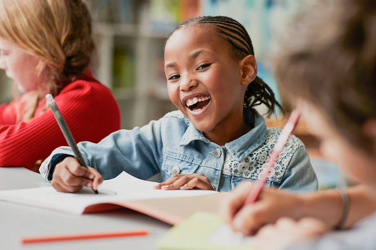 Portrait of schoolgirl drawing at the school library and laughing