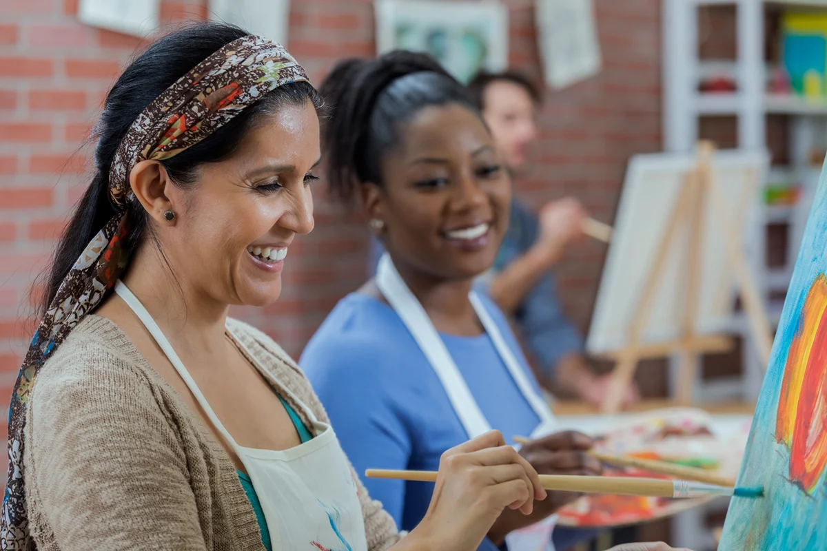 female friends paint together during art class