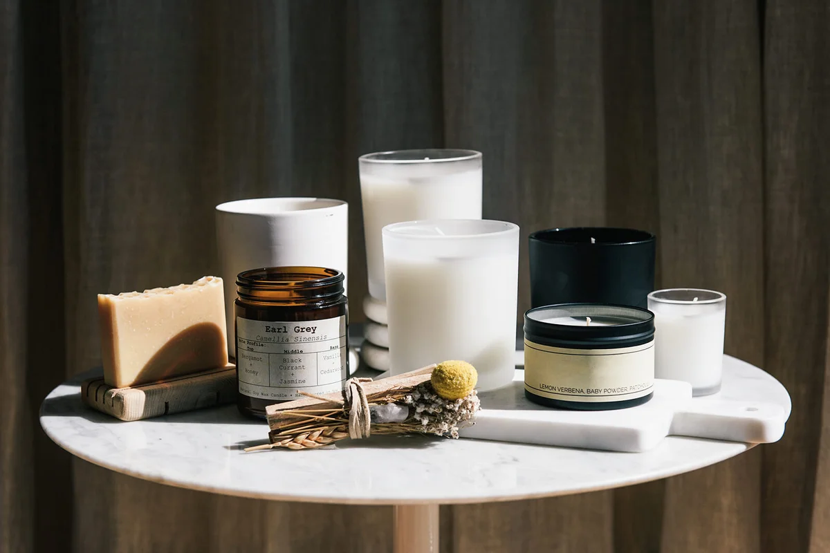 Home beauty products and candles sitting on a marble table in the sun