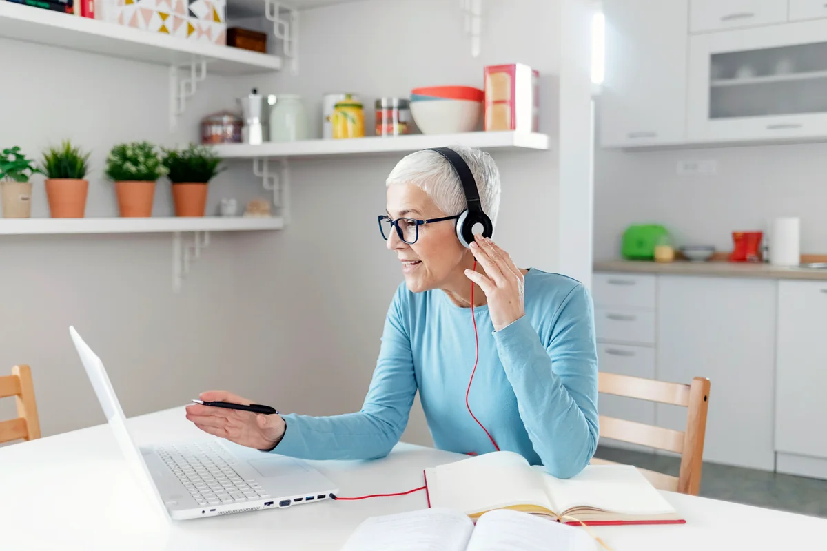 Senior Woman Learning Online With Headphones and Laptop at Home