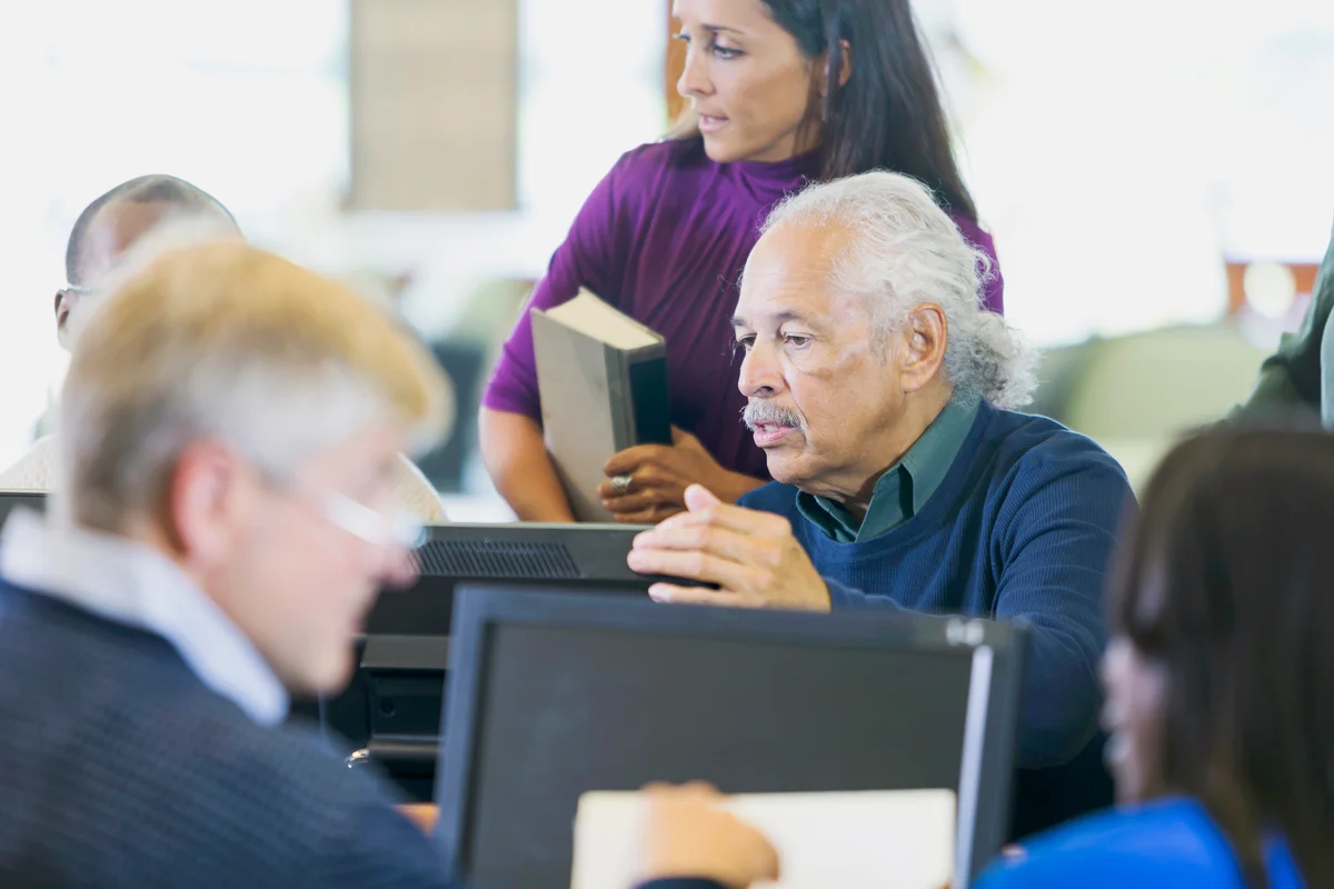 Group of senior citizens working on computers in the library