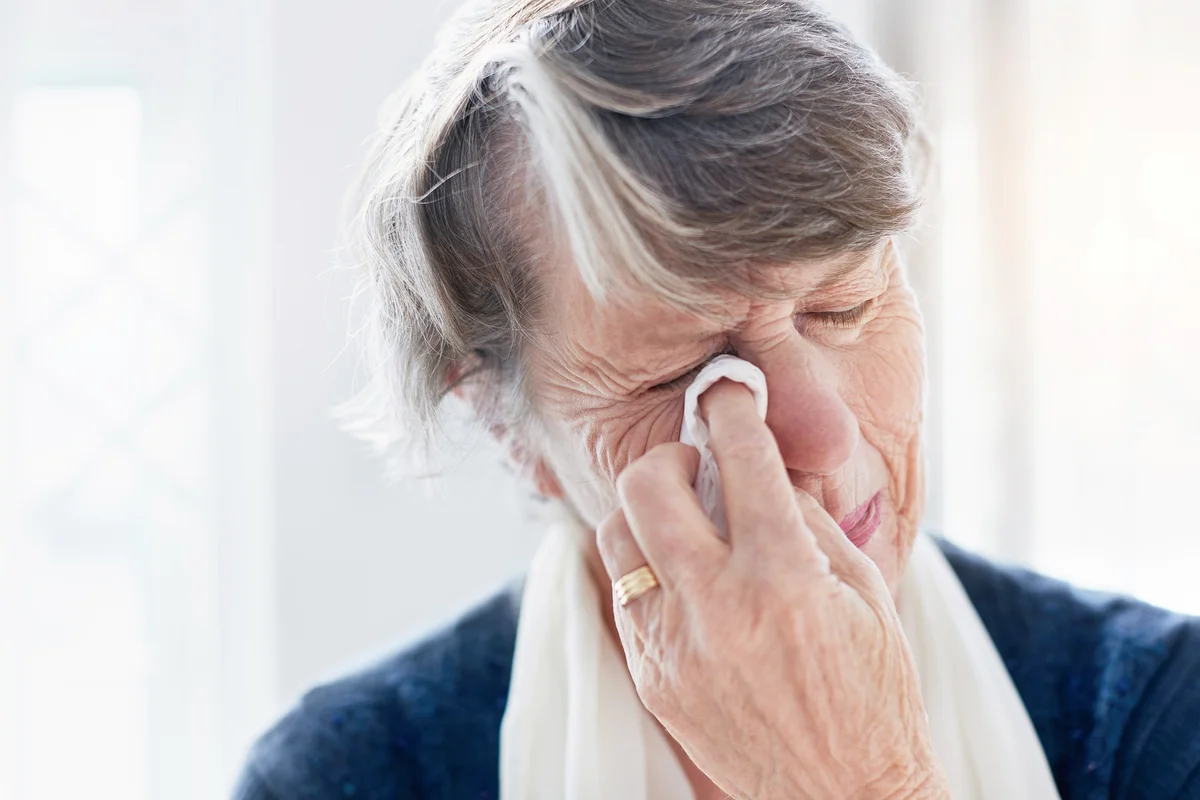 Weeping old woman wipes her eyes