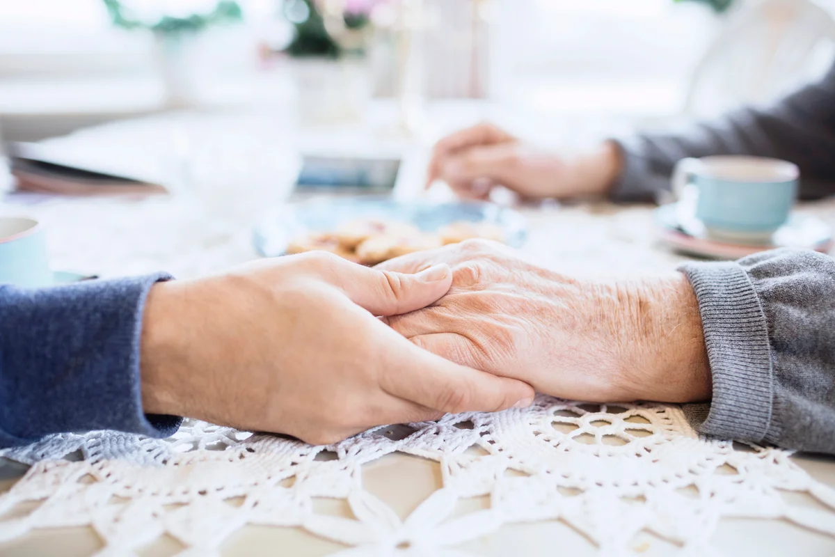 Friend consoling senior man at dining table