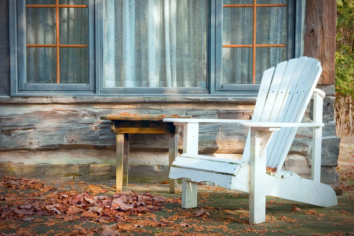 A white adirondack chair on a wooden deck