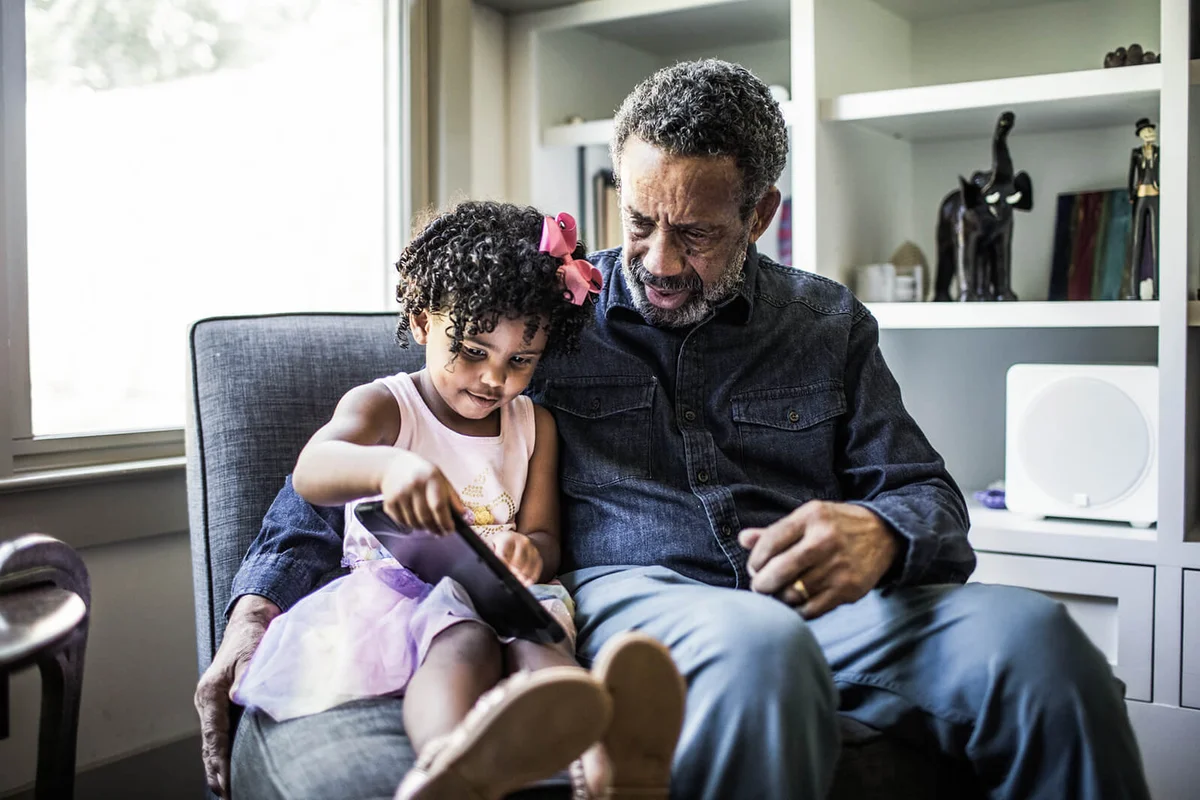 Granddaughter showing grandfather how to use tablet