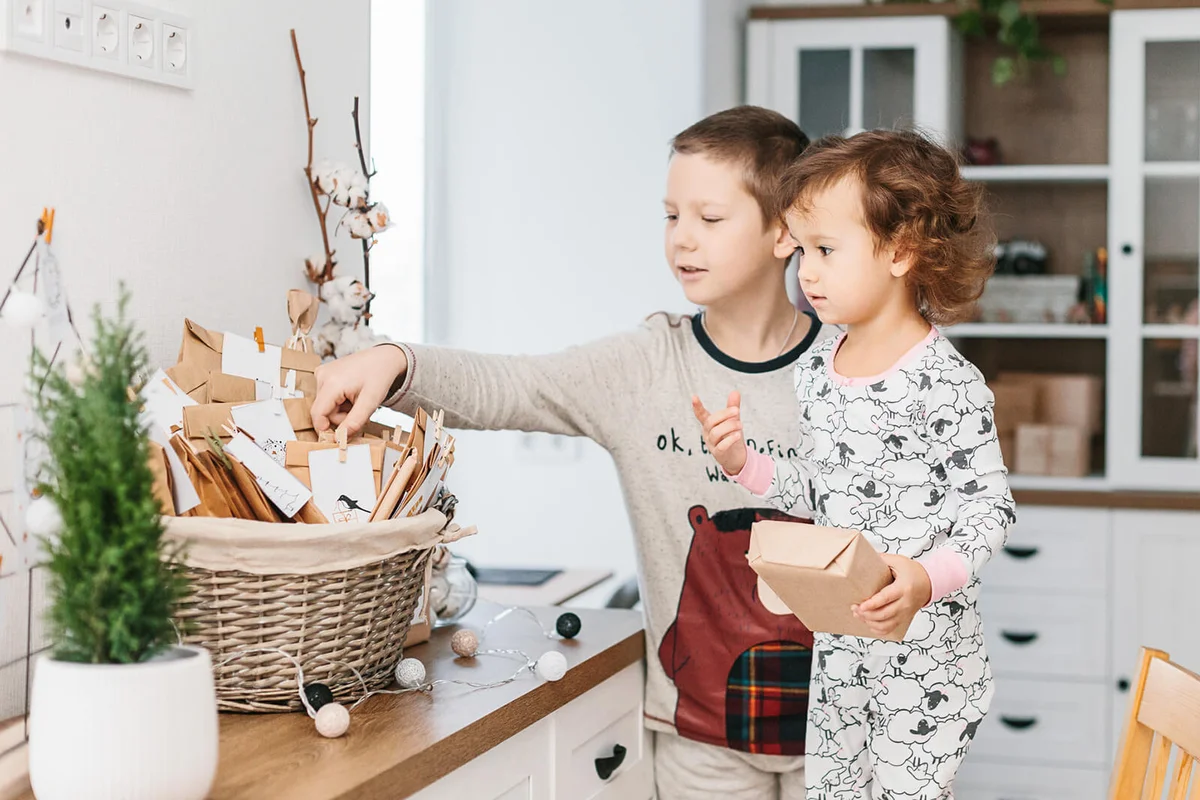 Children in pajamas and advent calendar with small gifts