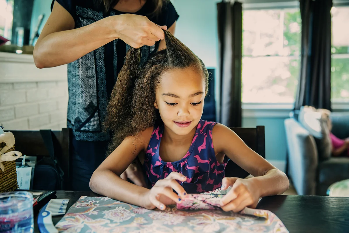mother braiding hair of daughter