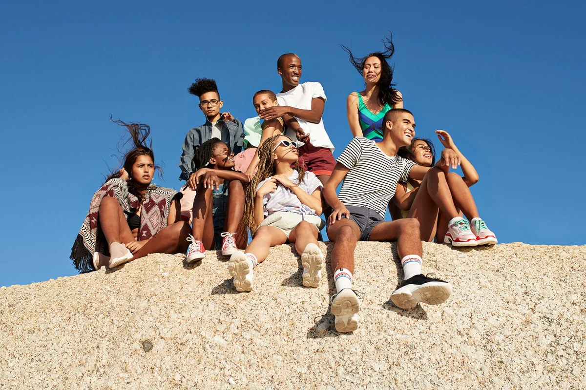 Multi-ethnic friends sitting together on rock