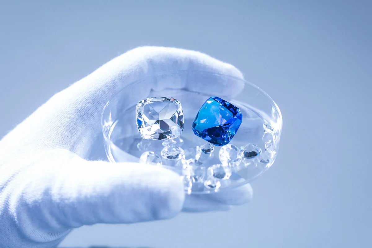 Jeweller inspecting replica diamonds in dish with gloved hand