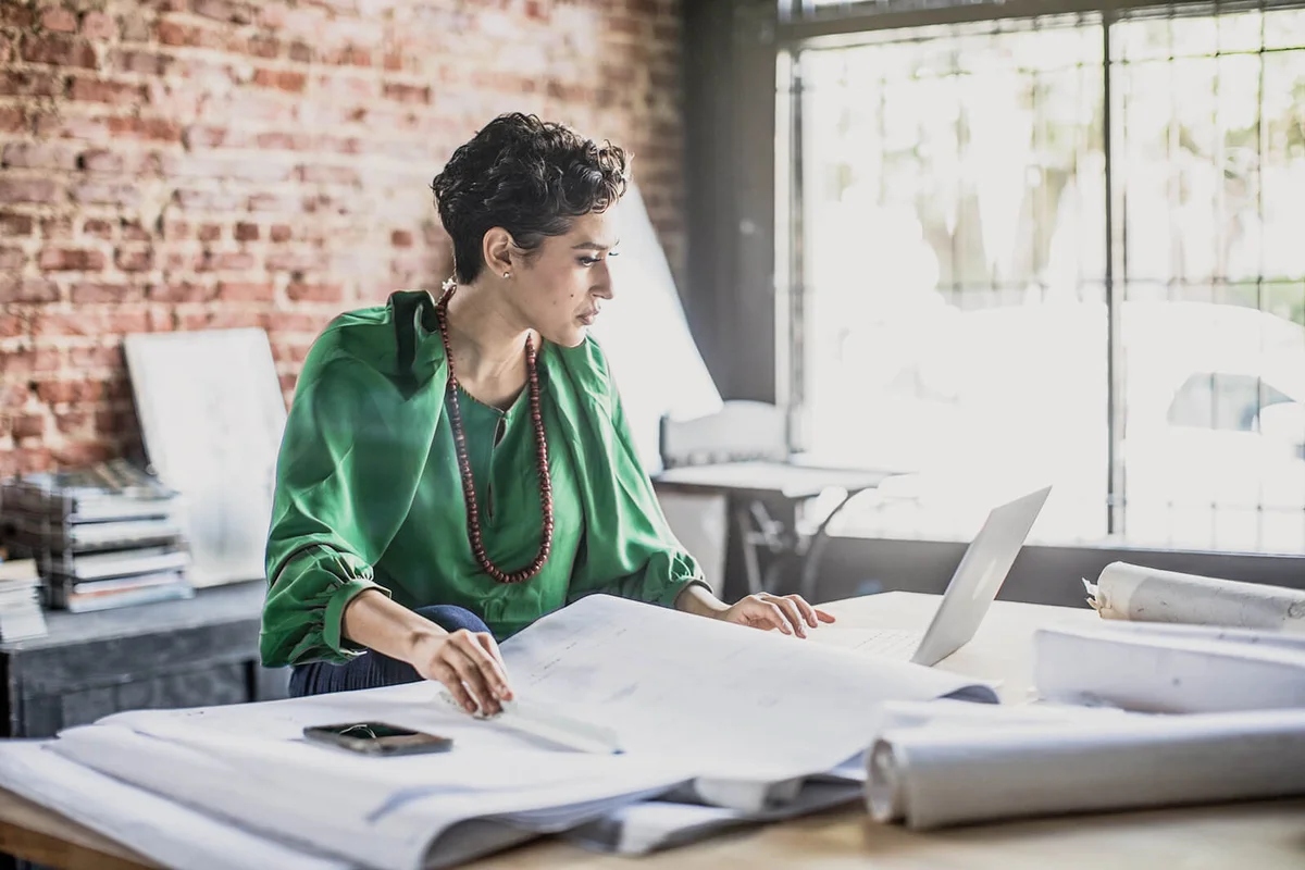 woman looking over architecture blueprints in office