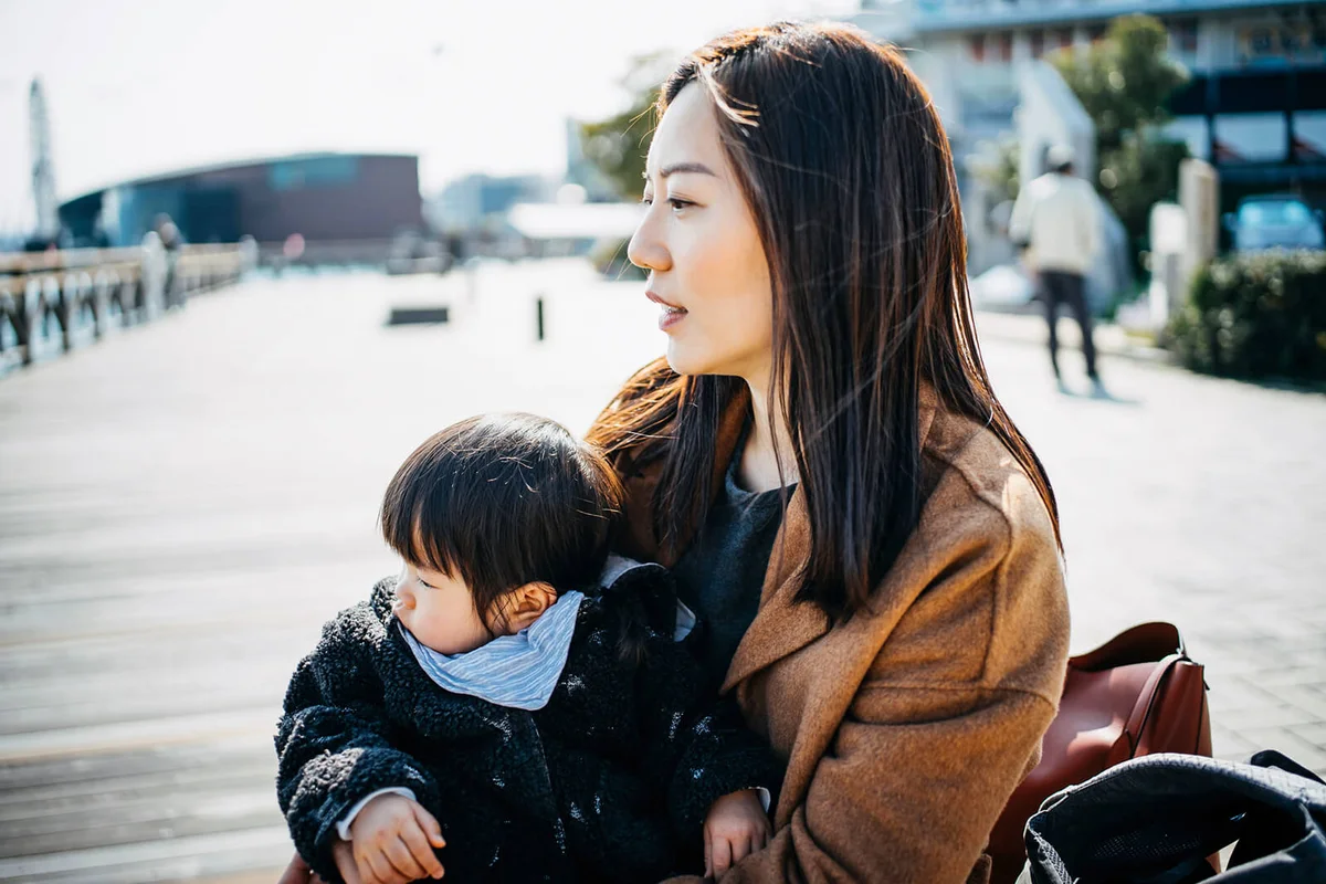 Young mother embracing cute little daughter on lap